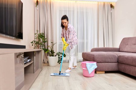 Téléchargez les photos : Femme heureuse nettoyage et nettoyage du sol au salon, ménage quotidien - en image libre de droit