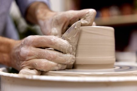 Téléchargez les photos : Mains masculines faisant tasse en céramique sur roue de poterie avec outil spécial en bois, Gros plan - en image libre de droit