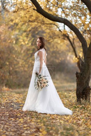 Foto de Hermosa novia feliz celebración de boda ramo de otoño en la naturaleza - Imagen libre de derechos