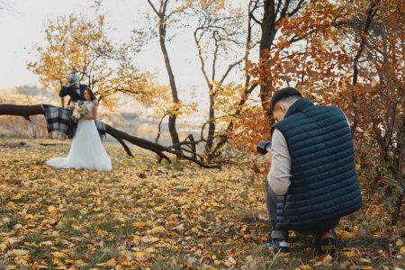 Foto de Fotógrafo de boda masculina tomar fotos de la novia y el novio al aire libre en otoño - Imagen libre de derechos