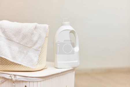 Téléchargez les photos : Gel de lavage ou détergent à lessive sur panier à linge blanc. Maquette, espace de copie. - en image libre de droit