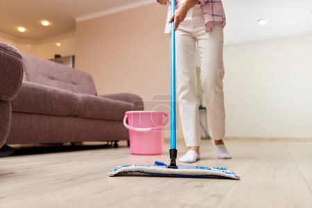 Téléchargez les photos : Jeune femme nettoyage et nettoyage du sol dans le salon, ménage quotidien, gros plan - en image libre de droit