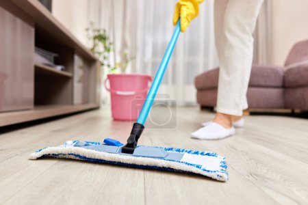 Téléchargez les photos : Jeune femme nettoyage et nettoyage du sol dans le salon, ménage quotidien, Cultivé - en image libre de droit