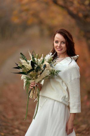 Foto de Hermosa novia feliz celebración de boda ramo de otoño en la naturaleza - Imagen libre de derechos