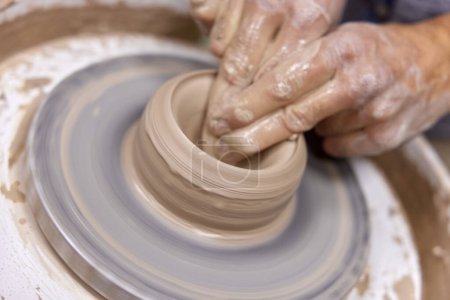 Téléchargez les photos : Mains masculines faisant tasse en céramique sur roue de poterie, Gros plan - en image libre de droit