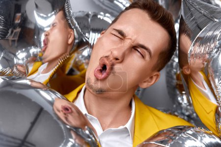 Photo for Portrait of happy man in yellow jacket with a lot of silver air balloons. birthday party - Royalty Free Image