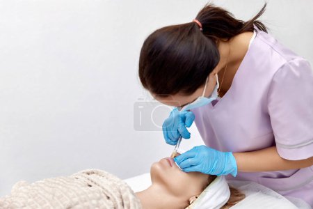 Foto de Esteticista hace inyecciones para agrandar los labios de la mujer hermosa. procedimiento labio aumento - Imagen libre de derechos