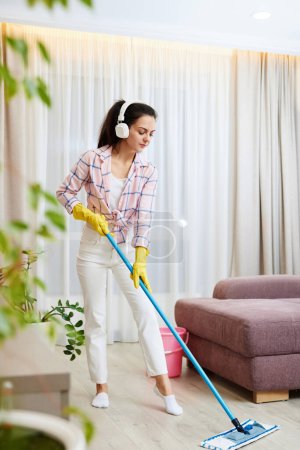 Photo for Happy woman singing and washing floor at living room, house chores. - Royalty Free Image