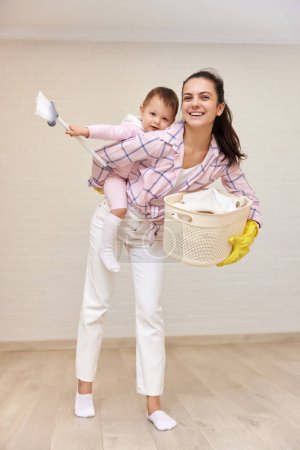 Photo for Happy mother housewife is holding cute baby girl and basket with laundry , Happy family - Royalty Free Image