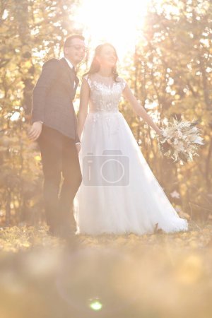 Photo for Beautiful bride in white wedding dress and groom standing outdoor on natural background in sunny day - Royalty Free Image