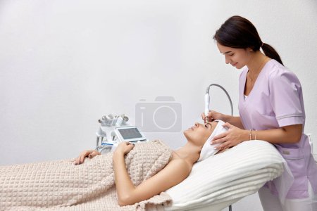 Photo for Cosmetologist doing peeling procedure for female client in beauty salon - Royalty Free Image