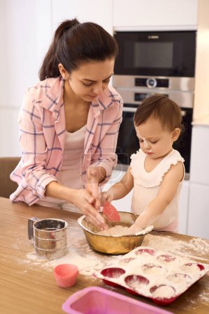 Foto de Madre y niña pequeña preparando la masa en la cocina, hornear galletas. feliz tiempo juntos - Imagen libre de derechos