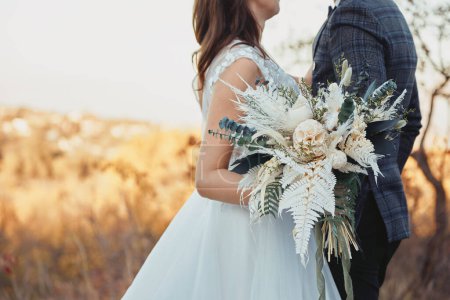 Téléchargez les photos : Mariée et marié tenant beau bouquet dans la nature en automne - en image libre de droit