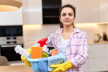 Photo for Woman in rubber protective yellow gloves holding cleaning tools. house chores. - Royalty Free Image