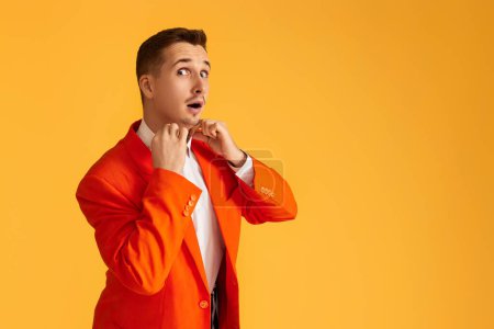 Photo for Cheerful extravagant young man in orange jacket on yellow background. - Royalty Free Image