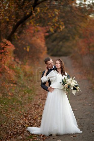 Photo for Happy bride in white wedding dress and groom standing outdoor on natural background - Royalty Free Image