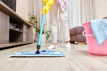 Foto de Mujer joven limpieza piso con fregona mojada en casa, limpieza diaria, primer plano - Imagen libre de derechos