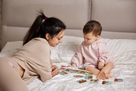 Photo for Beautiful mother playing playing with puzzle pieces with little child girl in bedroom - Royalty Free Image