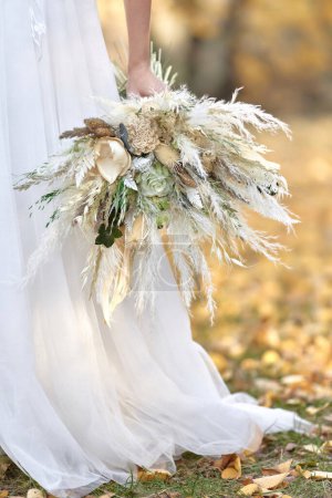 Foto de Manos de la novia sosteniendo hermoso ramo de otoño al aire libre - Imagen libre de derechos