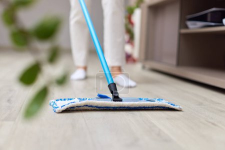 Téléchargez les photos : Jeune femme nettoyage et nettoyage du sol dans le salon, ménage quotidien, gros plan - en image libre de droit
