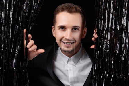 Photo for Happy handsome man in black jacket smiling on glitter background. - Royalty Free Image