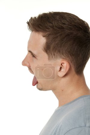 Photo for Young man shows her toung, feels disgust on white background. - Royalty Free Image