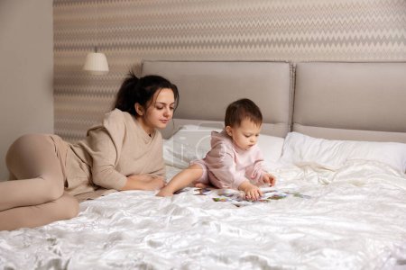 Foto de Madre caucásica jugando puzzle junto con su niña en el dormitorio - Imagen libre de derechos