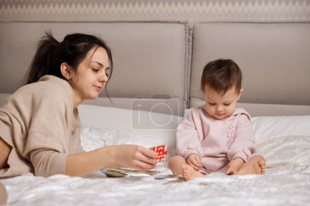 Téléchargez les photos : Jolie mère jouer puzzle avec son petit enfant fille dans chambre - en image libre de droit