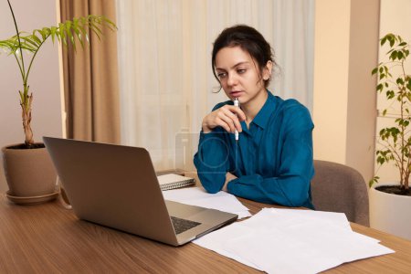 Téléchargez les photos : Belle femme d'affaires utilisant un ordinateur portable et communique avec le client sur Internet à la maison - en image libre de droit