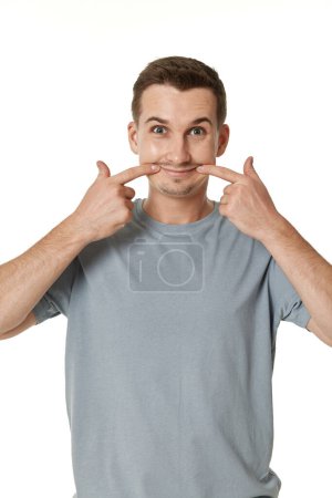 Téléchargez les photos : Portrait de jeune homme drôle souriant grimaçant sur fond blanc - en image libre de droit