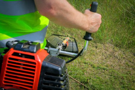 Photo for Worker mowing grass with grass trimmer - Royalty Free Image