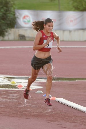 Foto de DENIZLI, TURQUÍA - 16 DE JULIO DE 2022: Atleta indefinido recorriendo 3000 metros de carrera durante el Campeonato de Atletismo Balcanes Sub-20 en la pista de atletismo Denizli Albayrak - Imagen libre de derechos