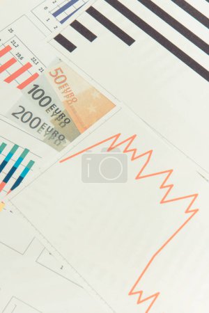 Téléchargez les photos : Monnaies euro et graphiques à la baisse représentant la crise financière causée par le coronavirus. Récession mondiale dans le monde - en image libre de droit