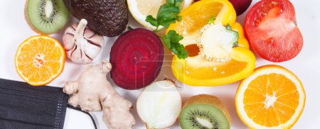 Photo for Fresh ripe fruits with vegetables and protective mask. Source healthy vitamins and minerals. Beneficial eating in times of Covid-19 - Royalty Free Image