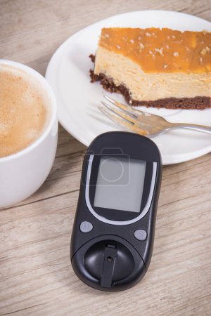 Téléchargez les photos : Glucomètre utilisé pour mesurer le niveau de sucre, gâteau au fromage doux et tasse de café avec du lait. Nutrition pendant le diabète concept - en image libre de droit