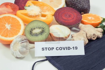 Inscription stop covid-19, fruits et légumes frais mûrs et sains contenant des vitamines naturelles et un masque protecteur. Stimulation immunitaire en temps de Covid-19