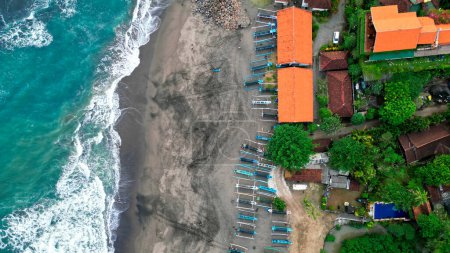 Téléchargez les photos : Bateaux de pêche reposant sur les rives d'une plage de sable noir à Bali, offrant une scène pittoresque où la tradition rencontre la tranquillité de l'étreinte de la nature. Images Aériennes 4K - en image libre de droit