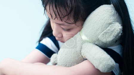 Foto de Una chica asiática solitaria abraza a un oso de peluche. Concepto de disputas familia y divorcio de los padres - Imagen libre de derechos