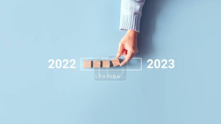 Verladen Neujahr 2022 bis 2023 mit Hand setzen Holzwürfel in Fortschrittsbalken. Start ins neue Jahr 2023 mit Zielplan, Zielkonzept, Strategie.