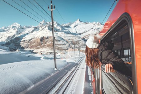 Photo for Happy woman traveler looks out from window traveling by train in beautiful winter mountains, Travel concept. - Royalty Free Image