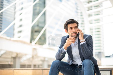 Foto de Primer plano de un joven caucásico hombre serio usando un dispositivo de teléfono inteligente moderno mientras está sentado en una zona pública. - Imagen libre de derechos