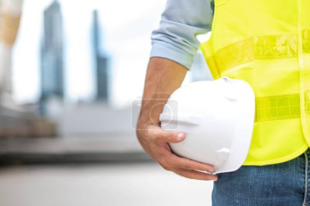 Photo for Engineer holding hardhat wearing yellow vest and standing ready for work safety in site. - Royalty Free Image