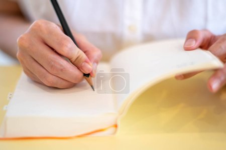 Photo for Female hand making notes with pencils and empty notebooks in their room. - Royalty Free Image