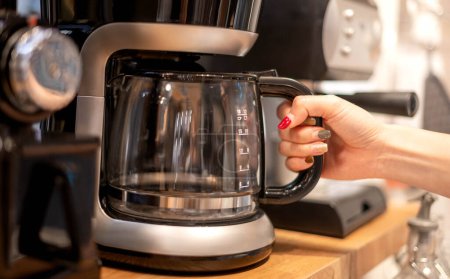 Téléchargez les photos : Main féminine utiliser une machine à café pour faire bouillir le café et préparer servir à leur client. - en image libre de droit