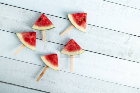 Photo for Table top shot of a watermelon popsicles isolated on light blue wooden background - Royalty Free Image