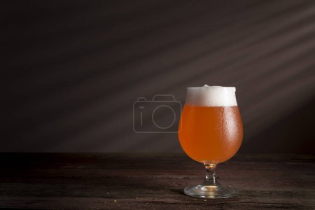 Foto de Vaso de cerveza de pomelo rojo frío sobre una mesa de madera rústica - Imagen libre de derechos