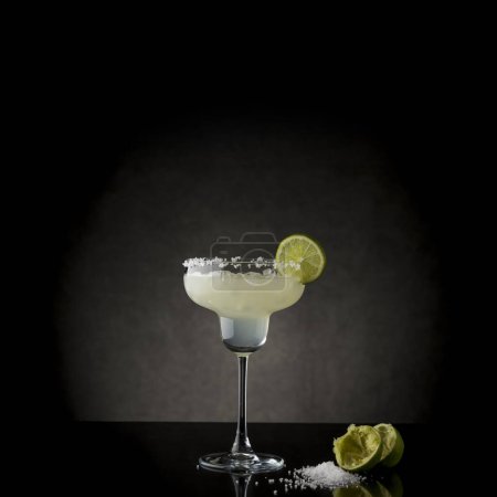 Téléchargez les photos : Cocktail classique de margarita au citron vert avec tequila, triple sec, jus de citron vert, glace concassée et un peu de sel sur le bord d'un verre, décoré avec une tranche de citron vert - en image libre de droit
