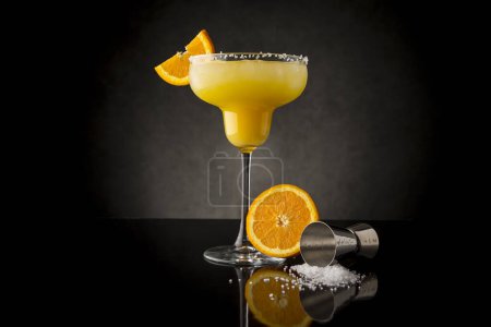 Foto de Cóctel de margarita de naranja con tequila, triple sec, zumo de naranja, hielo picado y un poco de sal en el borde de un vaso, decorado con una rebanada de naranja - Imagen libre de derechos