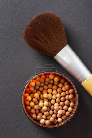 Photo for Flat lay of face powder pearls in an open powder box and a make up brush. Feminine cosmetics and make up products, bronzer and blusher. Selective focus on the bronzer pearls - Royalty Free Image