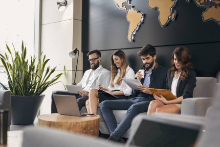 Photo for Group of business people sitting in an office building waiting room, waiting for a job interview. Focus on the people on the left - Royalty Free Image